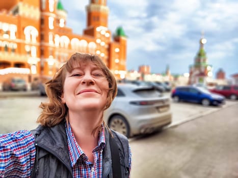 A middle-aged female traveler captures a joyful moment while exploring a lively city on a beautiful day.