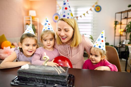Happy family gathering features children excited about cake and candles.