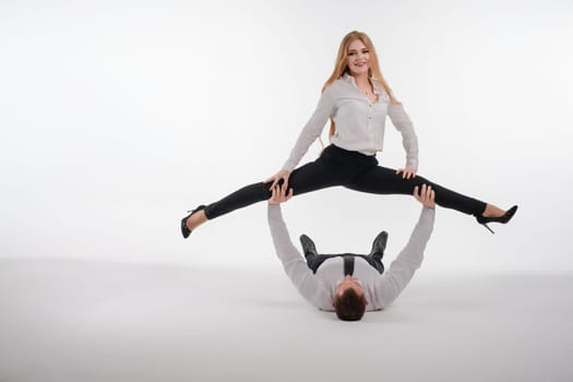 A couple showcases their skill and partnership as the woman performs a split while resting on the man's hands.