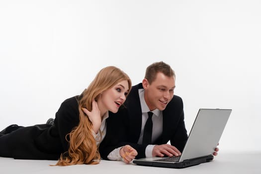 Two individuals engaged in a collaborative activity, smiling and focused on a laptop on a light background.