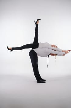 A couple showcases their athletic skills with a dynamic acrobatic pose in a professional setting, highlighting teamwork.