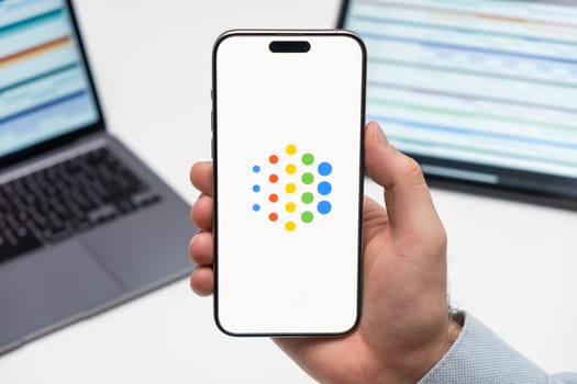 PRAGUE, CZECHIA - JULY, 2024: Google AI logo on the screen of smartphone in mans hand and laptop on the background