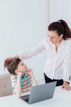 Female teacher helps boy on laptop to play online at school