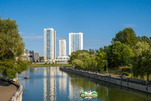 Minsk, Belarus - 08.16.24. Modern residential complex overlooking the river, surrounded by a green park, a combination of urban architecture and natura.
