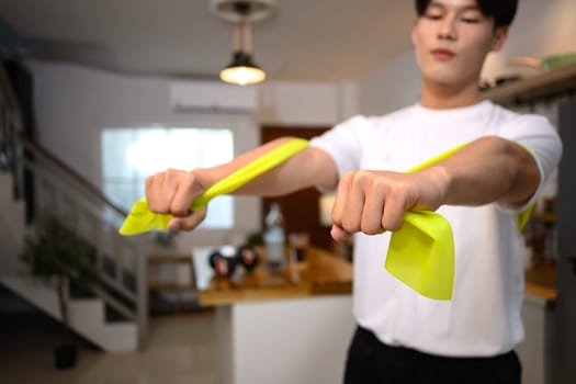 Young man stretching the band to work on his upper body strength.