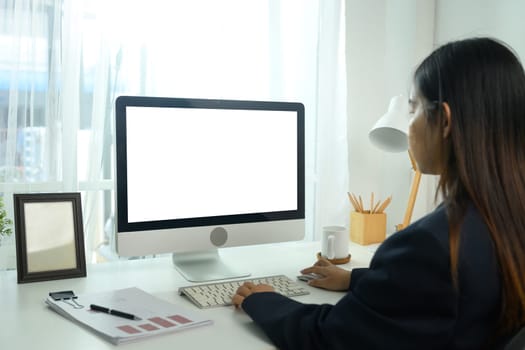 Side view of young businesswoman working on the computer at workplace with natural daylight.