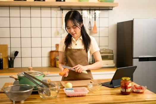Pretty young woman preparing ingredients for spaghetti in a cozy kitchen.