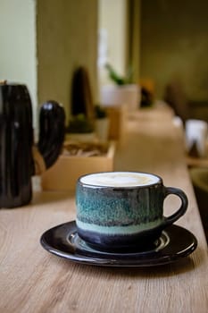 Coffee in blue cup on brown wooden table background. Sale discount. Close up cropped photo. Cappuccino in a art cup on a wooden table. A beautiful ceramic cup