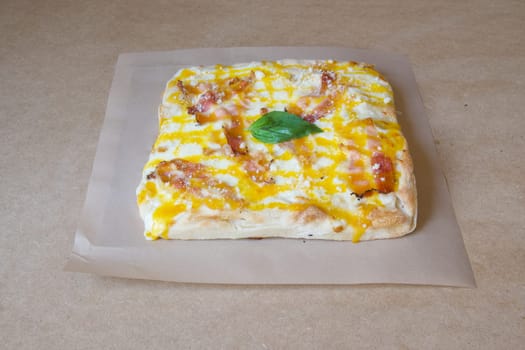 A slice of pizza with bacon and cheese on top. The pizza is sitting on a brown paper