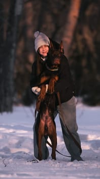 playing with a dog in nature. Doberman puppy with his owner. running with a puppy in the forest. winter frosty day in nature. puppy playing with its owner. raising a dog.