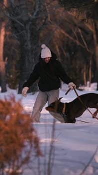 playing with a dog in nature. Doberman puppy with his owner. running with a puppy in the forest. winter frosty day in nature. puppy playing with its owner. raising a dog.