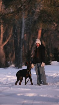 playing with a dog in nature. Doberman puppy with his owner. running with a puppy in the forest. winter frosty day in nature. puppy playing with its owner. raising a dog.