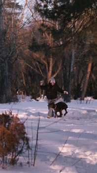 playing with a dog in nature. Doberman puppy with his owner. running with a puppy in the forest. winter frosty day in nature. puppy playing with its owner. raising a dog.