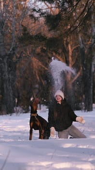 playing with a dog in nature. Doberman puppy with his owner. running with a puppy in the forest. winter frosty day in nature. puppy playing with its owner. raising a dog.