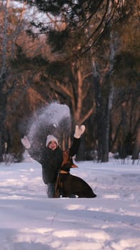 playing with a dog in nature. Doberman puppy with his owner. running with a puppy in the forest. winter frosty day in nature. puppy playing with its owner. raising a dog.