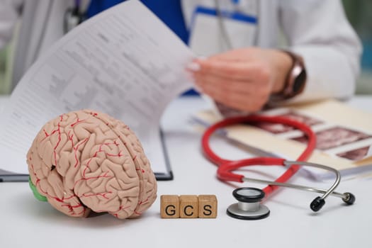 A doctor diligently reviewing patient files while utilizing a brain model and GCS cubes for comprehensive assessment