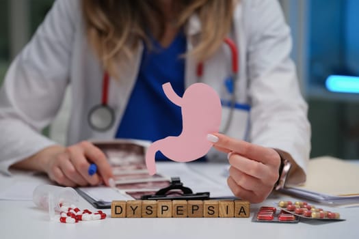 A healthcare professional examines dyspepsia using anatomical models and medications to understand the condition