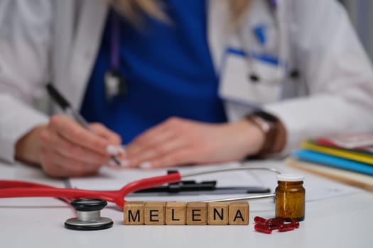 A healthcare worker writes notes on melena with medical items for better understanding and documentation
