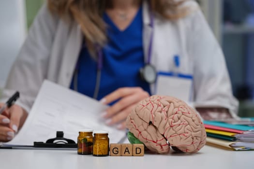 A medical professional reviews patient records using a brain model, GAD acronym, and jars of medicinal samples