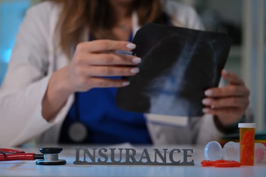 A healthcare professional carefully examines an Xray while discussing the implications of insurance coverage