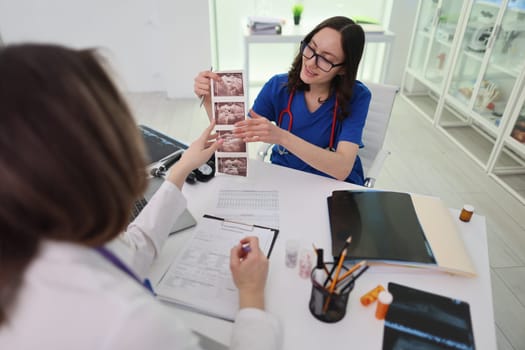 A medical professional carefully reviews diagnostic images with a colleague in a detailed clinical setting