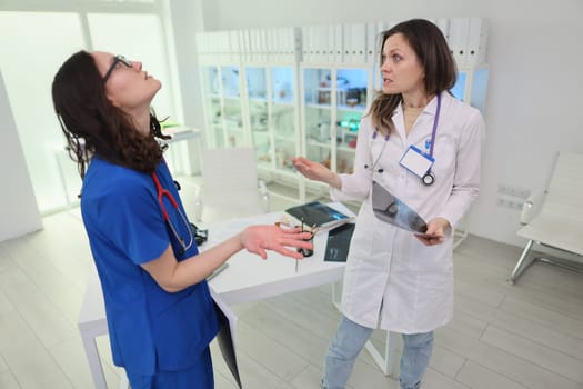 Two healthcare professionals engage in a conversation about patient care in a contemporary clinic setting.
