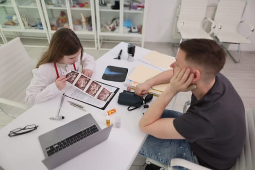 A healthcare professional is engaged in a conversation about medical images with a patient in a clinical setting