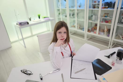 A thoughtful young girl is seated in a bright and contemporary office space, meticulously reviewing various documents