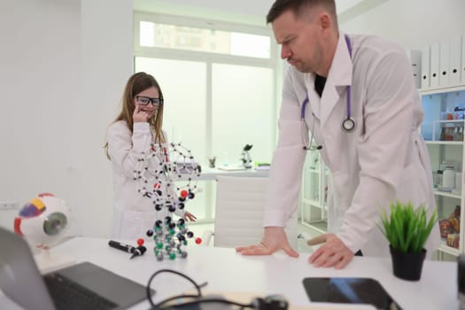 Two skilled healthcare experts are closely examining intricate molecular models within a modern laboratory environment