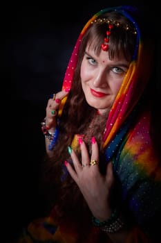 A mature woman with long hair styled beautifully poses in a colorful sari and dupatta, embracing Indian culture in a creative setting.