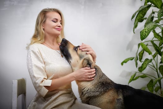 A middle-aged blonde blogger poses with her German shepherd, highlighting their strong bond in a lifestyle shoot.