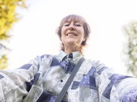 A traveler blogger smiles for a selfie, capturing the joy of her outdoor excursion in a natural setting on a sunny day.