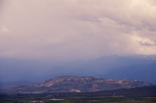 Layers of towering mountains blend seamlessly with rolling mists as dusk approaches, creating a serene atmosphere.