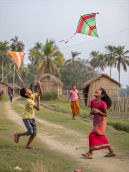 A lively scene of children playing and laughing during Bohag Bihu. Kids playing and laughing while flying colorful kites and throwing a balloon in a rural Indian village