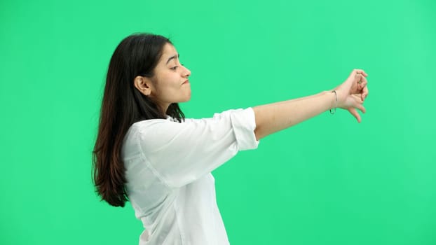 A woman, close-up, on a green background, shows her thumbs down.