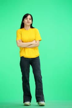 A woman, full-length, on a green background, crossed her arms.