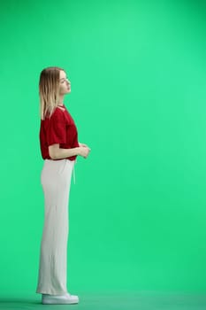 A woman, full-length, on a green background.