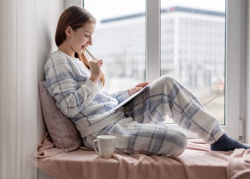 Teenage Girl Sitting On A Windowsill Writing Notes In Notebook And Planning Day, Vertical Video