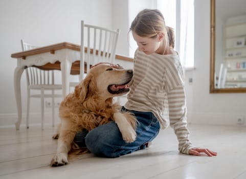 Smiling, A Happy Teenage Girl Hugs And Pets An Adorable Golden Retriever Dog At Home
