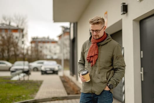 Young Attractive Man On A Street And Enjoys Coffee During Office Break Hour