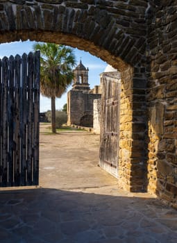 Mission San Jose near San Antonio with church seen through the stone entrance archway and wooden gate