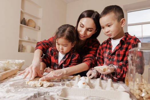 Happy mother and children baking together, family fun in the kitchen, messy hands, playful bonding, homemade cooking, joyful childhood moments.