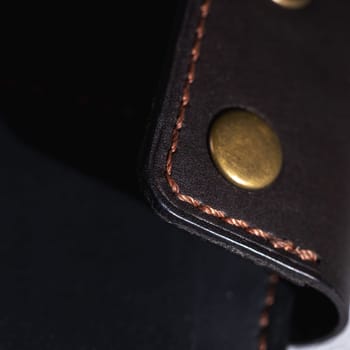 Close up showcasing the craftsmanship of a leather wallet, highlighting the detailed stitching and brass rivets