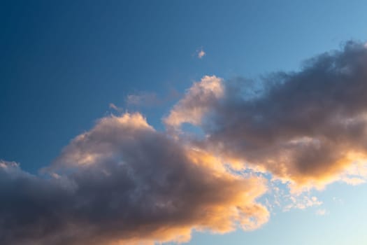 Beautiful sunset illuminating cumulus clouds with orange and yellow hues against a deep blue sky