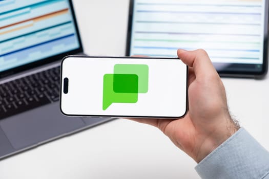 PRAGUE, CZECH REPUBLIC - JANUARY 21 2025: Google chat logo on the screen of a cell phone in business mans hand and laptop on the background.