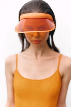Fashionable female model showcasing a vibrant orange visor and dress against a minimalist white background, perfect for summer-themed editorial content.