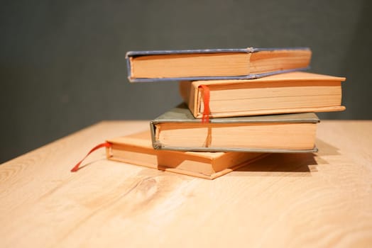 A collection of vintage books stacked neatly on a wooden table.