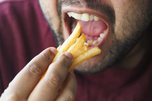 A person is eating golden fries with evident delight.