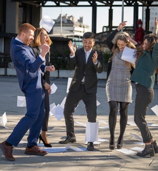 Excited businesspeople throwing paperwork in the air, celebrating a success
