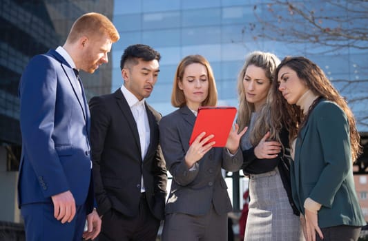 Businesspeople working together using a tablet outside of their office building